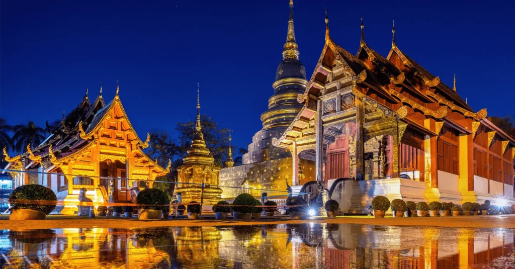 Thai temple illuminated at night, showcasing ornate architecture and serene ambiance.