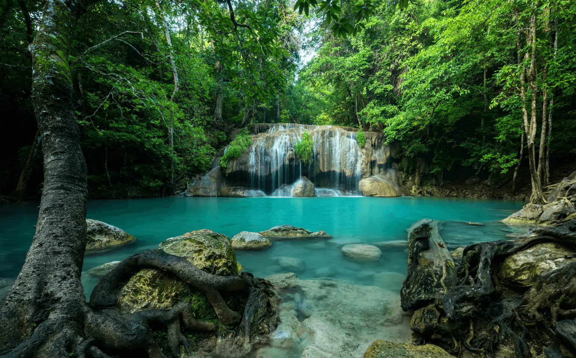 Majestic waterfall cascading down rocky cliffs surrounded by lush greenery.